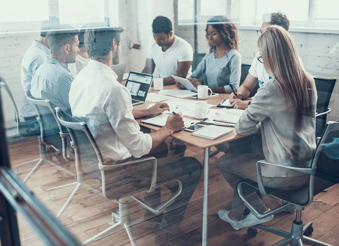 Captive Insurance Management - Confident Business Directors Discussing Productive Strategy during a Brainstorming Meeting with Laptops in a Large Conference Room1